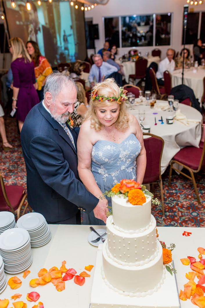 A milestone wedding couple cuts a wedding cake.