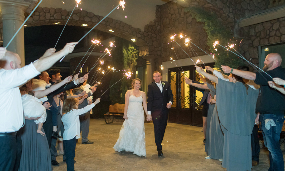 Newlyweds with sparklers say goodbye to guests at night, a beautiful end to the wedding day.