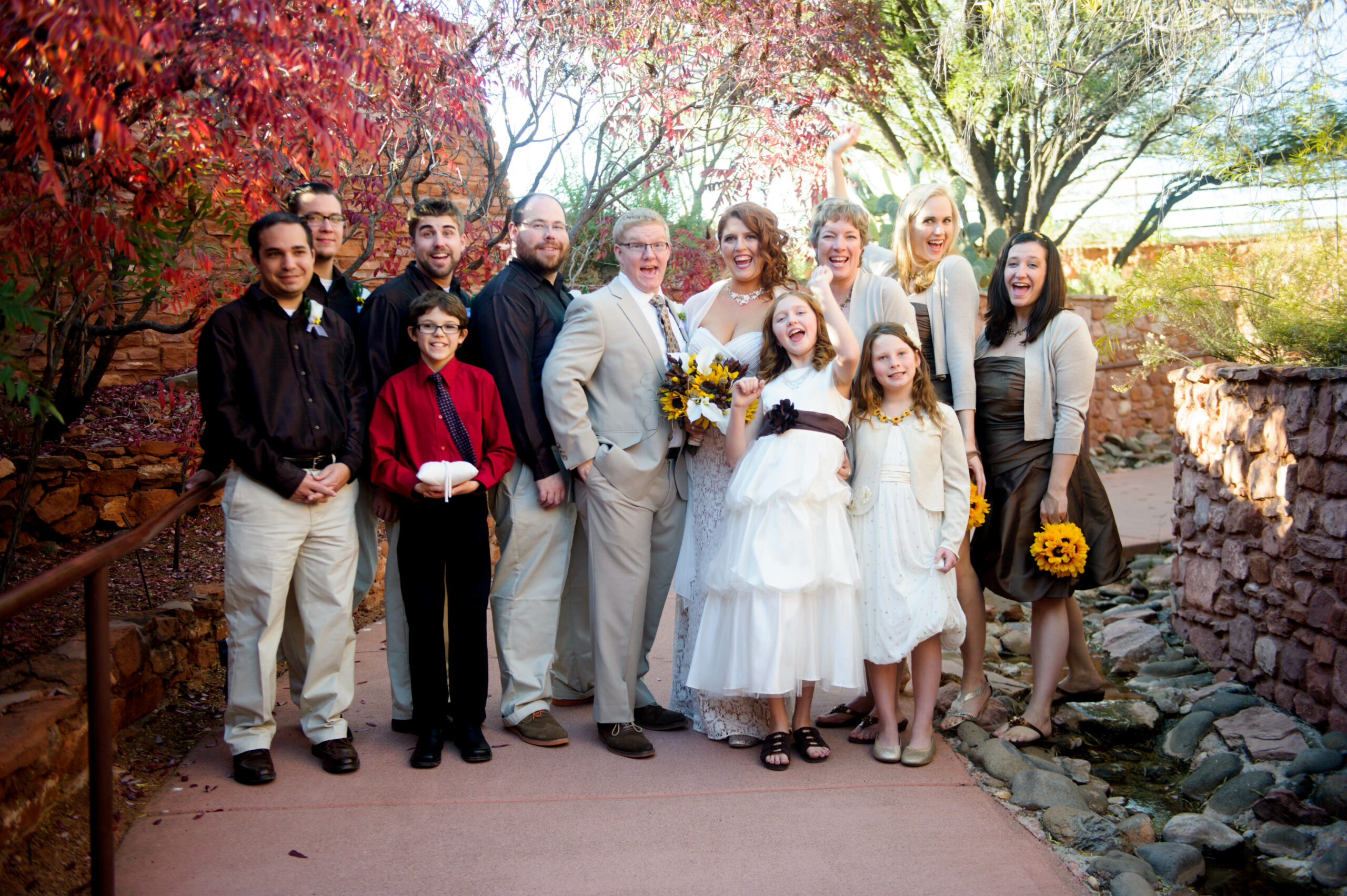 A young newly wedded couple poses for a photo with flower girls, bridesmaid, and best man.
