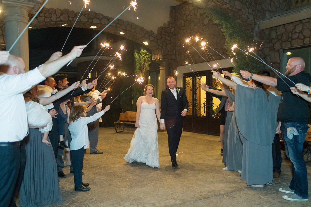 Newlyweds with sparklers say goodbye to guests at night, a beautiful end to the wedding day.