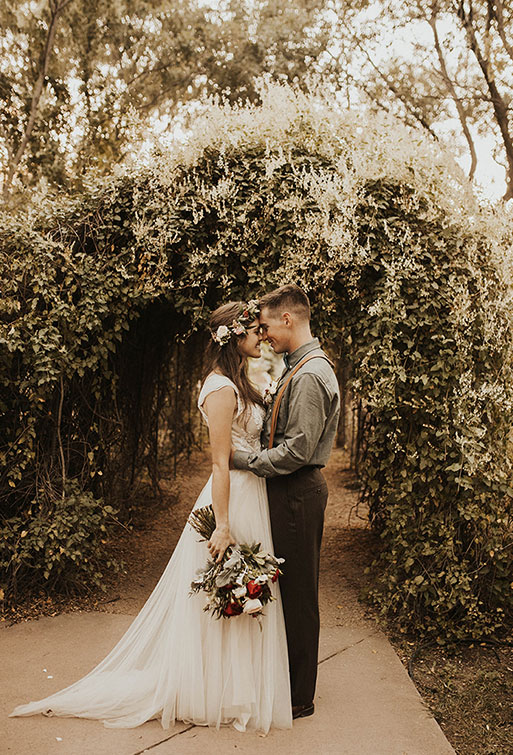 A young newly wedded couple poses for a photo in their wedding attire.